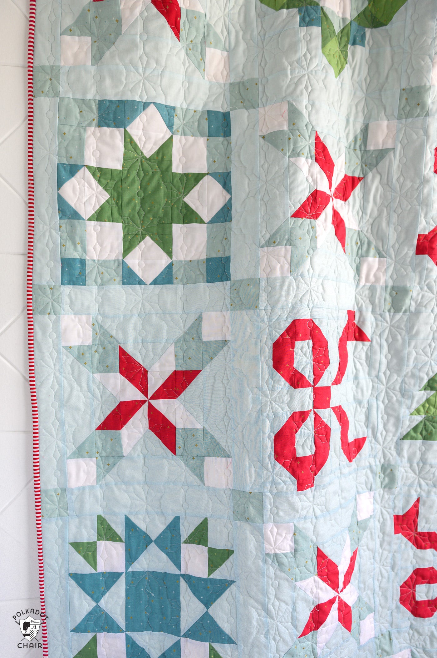 Quilt with star patterns in red, green, and blue on a light background