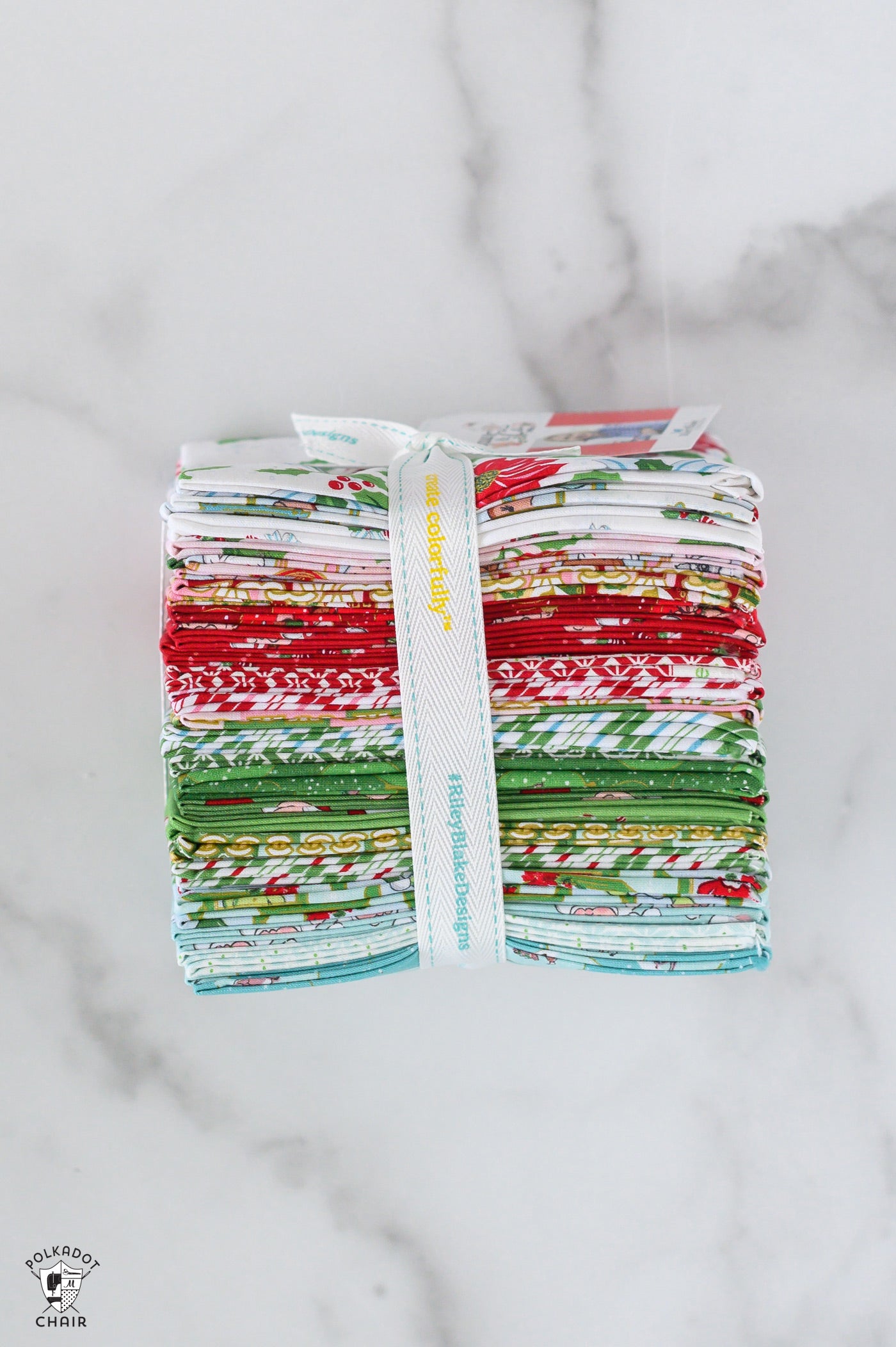 Stack of colorful fabric bundles tied with a white ribbon on a marble surface