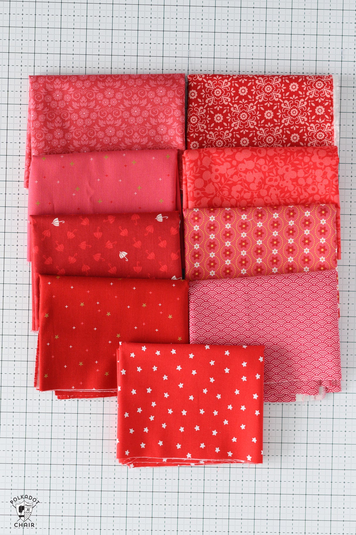 Collection of red fabric squares with various patterns on a grid background