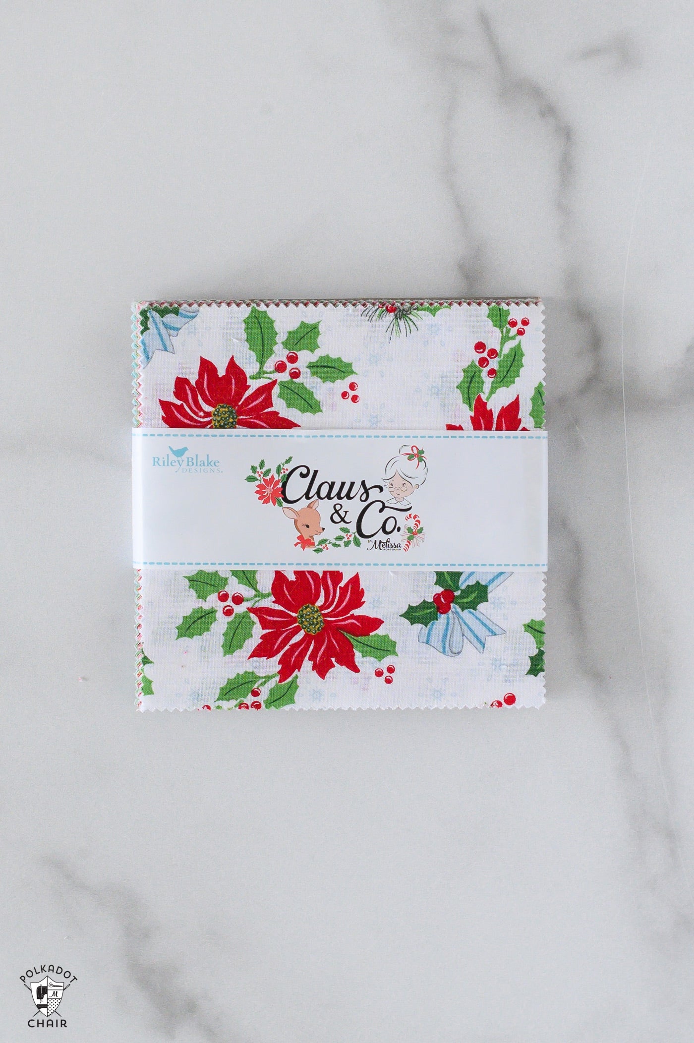 Christmas-themed fabric panel with 'Claus & Co' branding on a marble surface