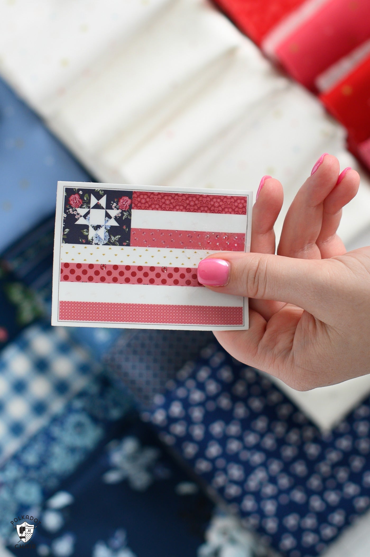 Hand holding a small quilt square with a star pattern against a fabric background