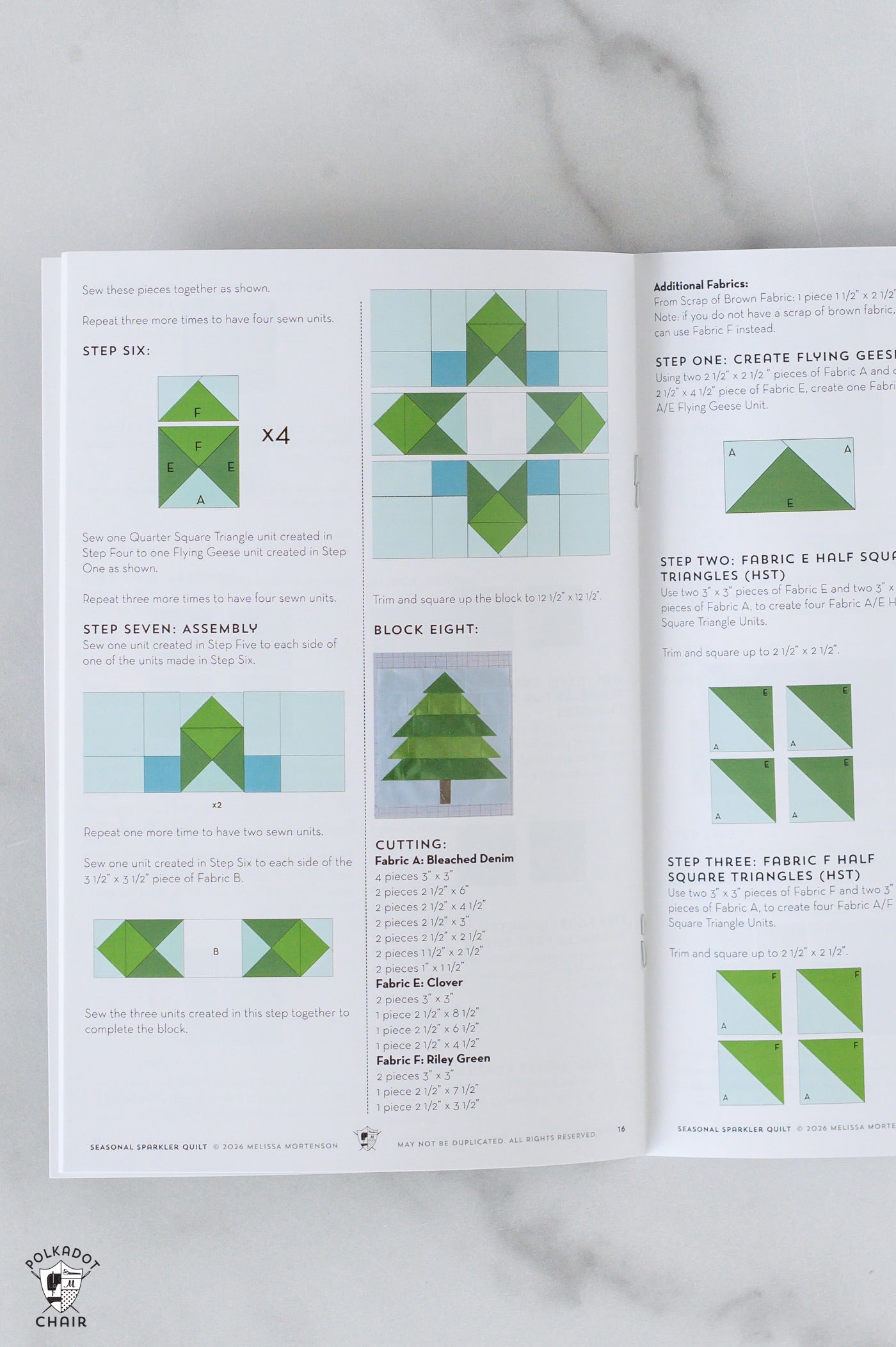 Open book with quilt pattern instructions on a marble surface