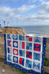 red white and blue nautical quilt out doors in front of light house and ocean