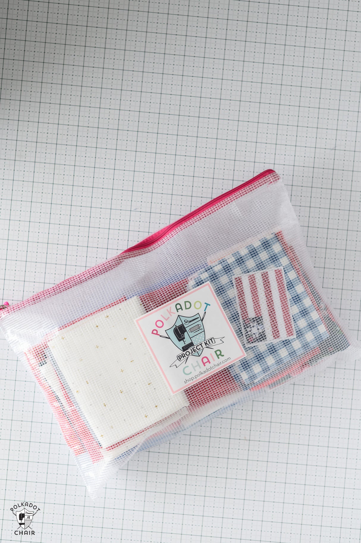 Clear pouch with a red and white checkered lining, containing a bar of soap and a small bag, on a grid background.