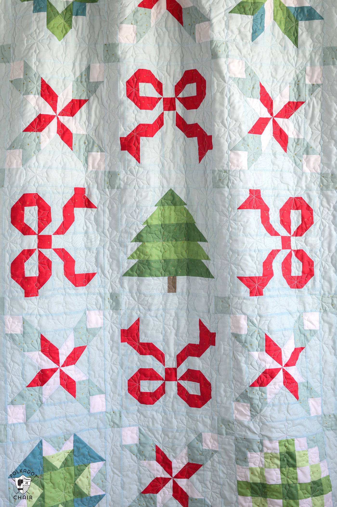 Quilt with red bows and green trees on a light blue background